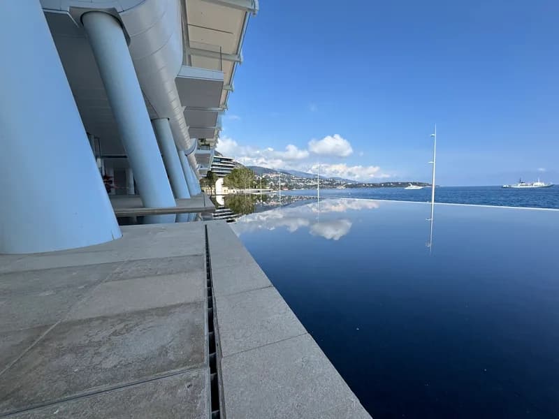 View across the mirrored water feature at the base of Le Renzo, looking east towards Roquebrune-Cap-Martin