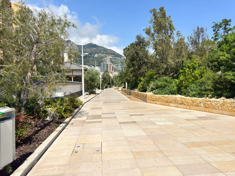 The Vallee de la Pinede shaded walkway in Monaco connecting Jardin d'Eau apartments and the Japanese Garden, leading directly towards the Larvotto promenade